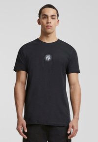 Zwart katoenen T-shirt met een ronde hals en korte mouwen, met een gecentreerd circulair logo in grijs en zwart op de borst.