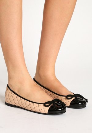 Bailarinas con una parte superior de tela nude que presenta un patrón de cuadrícula en diamante negro. Punta de charol negro y un lazo decorativo en el empeine.