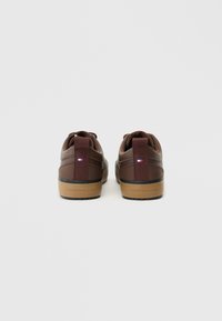 Brązowe skórzane sneakersy z siateczkowymi akcentami, tanowym gumowym półbasem i małym logotypem na pięcie. Okrągły nos i sznurowana konstrukcja.