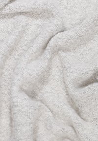 Tissu doux et texturé aux tons gris clair avec une apparence tissée duveteuse, présentant de subtiles variations de couleur et de profondeur.