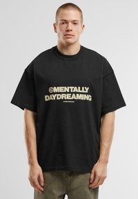 Juodas oversized medvilnės marškinėliai trumpomis rankovėmis, priekyje pavaizduoti drąsūs bežiniai užrašai "MENTALLY DAYDREAMING".