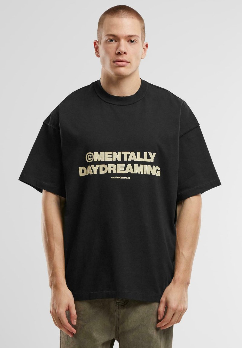 Juodas oversized medvilnės marškinėliai trumpomis rankovėmis, priekyje pavaizduoti drąsūs bežiniai užrašai "MENTALLY DAYDREAMING".