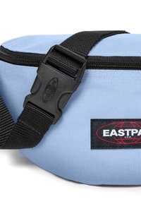 Tyrkysová ledvinka s texturovanou tkaninou, černým popruhem a plastovou sponou. Na černém klínu se nachází výrazné logo Eastpak.