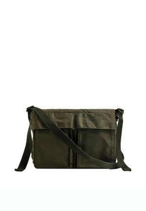 Sac bandoulière rectangulaire vert foncé avec deux poches avant et une bandoulière réglable sur fond blanc.