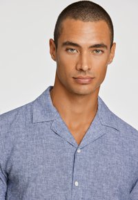 Korte mouwen, colbert in lichtblauwe linnenmix, met een gestructureerde stof en een knoopsluiting aan de voorkant.