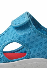 Niebieskie sandały z fakturowym wierzchem z perforowanym wzorem w kropki, z rzepem i kontrastującą czerwoną wkładką. Biała gumowa podeszwa z gripem.