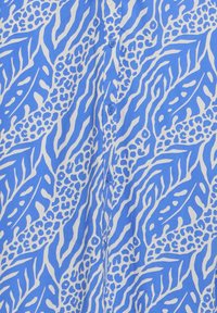 Modrý a biely blúzkový materiál s abstraktným zvieracím vzorom a viditeľnými gombíkmi pozdĺž stredového švu.