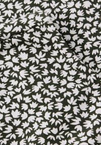 Tessuto di cotone con uno sfondo verde scuro e intricate decorazioni a foglia bianche. La superficie texturizzata e rigata crea profondità e interesse.