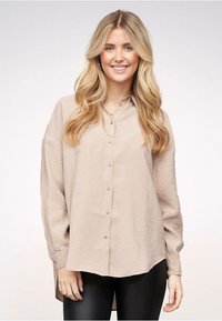 Lys beige skjorte med knaplukning, afslappet pasform, lange ærmer og rundet kant, der har en subtil glans og blanke knapper.