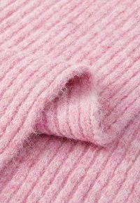 Ribbed pink knit fabric with a soft, fuzzy texture. Layers gently folded to reveal the varying shades of pink in the yarn.