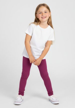 Biała koszulka z krótkim rękawem i fioletowe legginsy na dziecku, w połączeniu z białymi trampkami z kolorowymi akcentami. Prosty design, dopasowany krój.