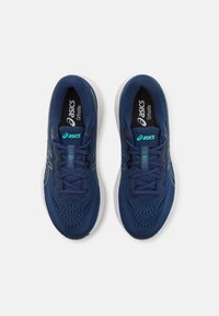 Blauwe sportieve schoenen met een bovenwerk van mesh, ivoorkleurige tussenzool en een zwarte binnenzool. Voorzien van veters en een logo in turquoise.