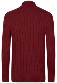 Suéter rojo de punto con cuello alto, con un patrón de trenzas texturizado y puños y dobladillo de canalé.