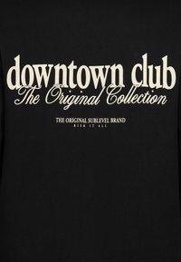 Schwarzer Sweatshirt mit weißem Text, der "downtown club The Original Collection" und "THE ORIGINAL SUBLEVEL BRAND RISK IT ALL" lautet.