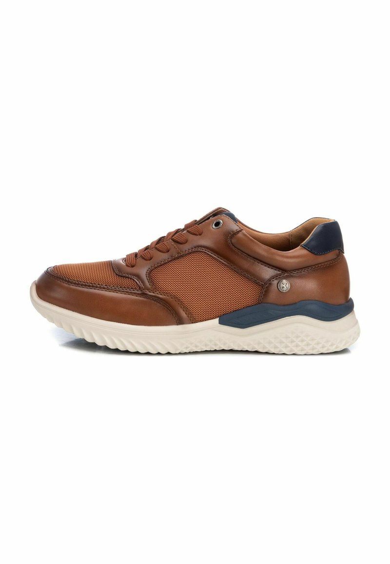 Zapatilla de cuero marrón con detalles de malla, cuello acolchado, suela beige, acentos texturizados y cierre con cordones. Vista lateral con elementos de color de contraste.