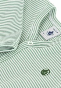 Tessuto verde a righe con una consistenza morbida, caratterizzato da sottili righe bianche e un logo circolare in verde scuro. Include un piccolo bottone a scatto.