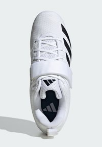 Biały but sportowy z teksturowaną cholewką, czarnymi paskami, wzmocnionym czubkiem i paskiem na rzep. Posiada wyściełany kołnierz i czarną wkładkę.