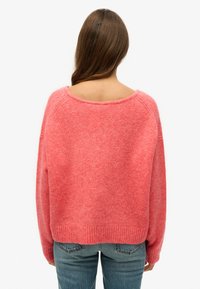 Przesadny sweter z okrągłym dekoltem, wykonany z mieszanki jasnoróżowej i ciemnoróżowej wełny, z prążkowanymi ściągaczami i dołem, o miękkiej, puszystej fakturze.