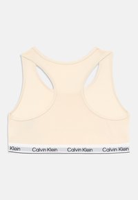 Bežinis sportinis liemenukas su balta elastinga juosta, ant kurios pakartotinai užrašytas "Calvin Klein" logotipas juodu tekstu.