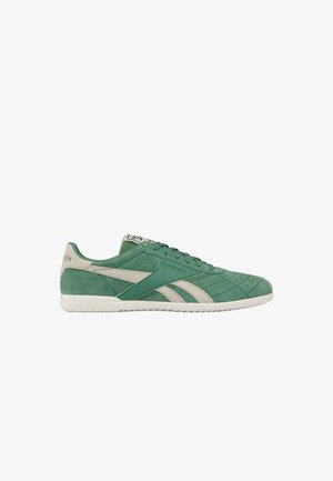 Groene suède Reebok sneaker met creme accenten, veterontwerp en een witte rubberen zool, zijaanzicht op een witte achtergrond.