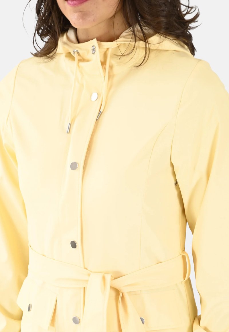 Veste imperméable jaune avec capuche à cordon de serrage, boutons-pression et taille ceinturée. Elle possède un tissu lisse et des poches latérales.