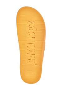 Semelle de chaussure en caoutchouc orange avec des rainures texturées et un logo. Présente des lettres en relief et un bord lisse, conçue pour l'adhérence et le confort.
