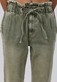 Groene denim broek met een gegatherde elastische tailleband en trekkoord. Heeft zijzakken en een relaxte pasvorm met een licht vervaagde textuur.