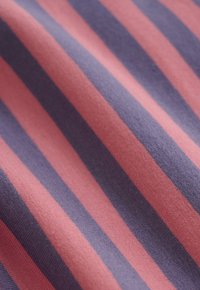 Close-up van een stof met diagonale roze en paarse strepen en een zachte, gestructureerde breioppervlakte.
