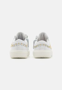 Sneakers bianchi con una superficie testurizzata, caratterizzati da borchie decorative dorate e accenti blu chiaro sul tallone. Suola in gomma, design low-top.