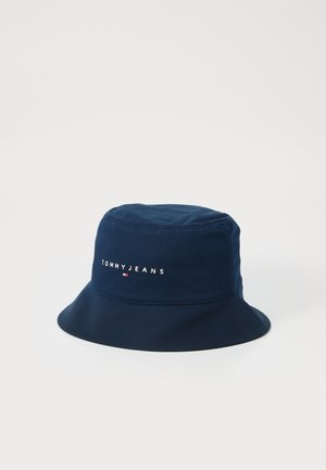 Marinblå bøttehatt laget av mykt stoff med en brodert "TOMMYJEANS" logo og en liten rød og hvit detalj. Rund design med bred skjerm.