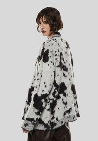 Maglione a maglia con motivo dalmata in bianco e nero, caratterizzato da una vestibilità morbida, maniche lunghe, polsini a coste e orlo arrotondato. Texture morbida.