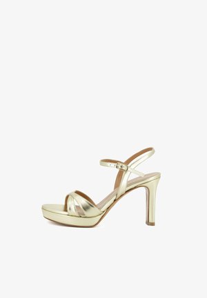 Sandalo dorato con tacco alto, cinturino alla caviglia, punta aperta e leggera zeppa, mostrato su sfondo bianco.
