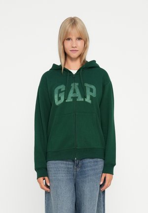 Zelená mikina na zips vyrobená z bavlnenej zmesi, s veľkým logom "GAP" v svetlejšej zelenej, so šnúrkami na kapucni a prednými vreckami.