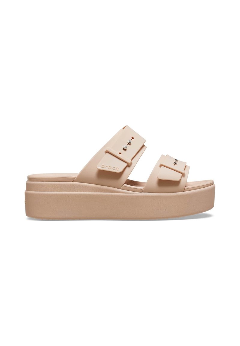 Helle beige Plattform-Sandalen mit zwei breiten Riemen, die mit dekorativen Nieten versehen sind. Sie bestehen aus strapazierfähigem Material und haben eine glatte, strukturierte Sohle.