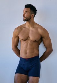 Boxer da uomo di colore blu navy, realizzati in tessuto morbido con vita rossa e logo, caratterizzati da un taglio aderente e apertura frontale. Texture liscia senza motivi.