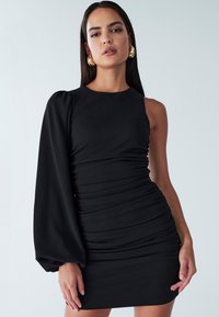 Melna kleita ar vienu garu, pūkainu piedurkni un savilkta tekstūru. Pielāgota silueta, izceļ gludu audumu un minimālistisku dizainu.