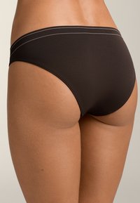 Barna pamut bikini alsó, sima textúrával, két kontrasztos fehér vízszintes csíkkal a derékrészen. Nincsenek egyéb figyelemre méltó részletek.