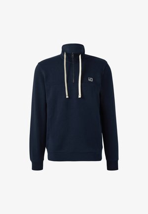 Tumesinine pehme dressipluus, millel on pooltõmblukk, kõrge krae, kreemilised paelad, ees rindkerepanel ja soonikkoes varrukad ja alläär.