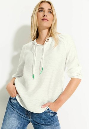 Witte pullover met textuur, driekwartmouwen en een ronde onderkant. Het heeft een trekkoord bij de hals met groene accenten en een comfortabele pasvorm.
