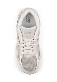 Botte de sport beige avec des panneaux en maille et en daim, bout renforcé et col rembourré. Dispose de lacets plats et d'un logo sur la languette.