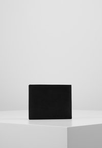 Schwarze Wildlederbörse in rechteckiger Form, mit gesteppten Kanten und glatter Oberfläche. Minimalistisches Design ohne sichtbare Beschläge oder Akzente.