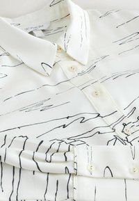 Cămașă albă cu model abstract de linii negre, design cu guler, închidere cu nasturi în față și textură netedă. Croială clasică cu mâneci scurte.