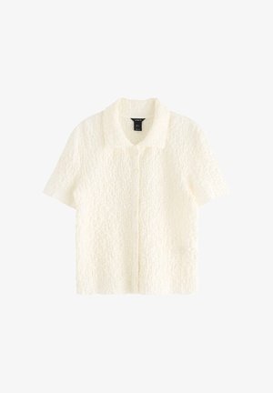 Korta ärmar, knäppskjorta i texturerad vit tyg. Har en krage och en avslappnad passform.