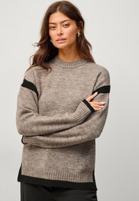 Maglione a maglia marrone con dettagli neri sulle maniche e sull'orlo. Presenta un collo rotondo e polsini a costine, con una vestibilità rilassata.