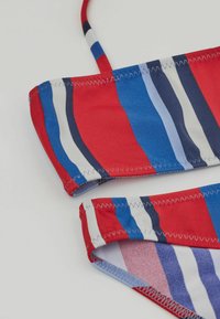 Röd och blå randig bikini med horisontella linjer, som har flera nyanser och en mjuk, elastisk textur. Inkluderar smala band och sydda kanter.
