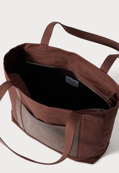 Barna vászon válltáska cipzáras záródással, az elején texturált rókamintával. Tartós anyagból készült, puha tapintású és hosszú fogantyúkkal rendelkezik.