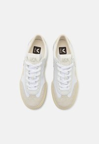 White and beige sneakers with a soft suede toe cap, mesh sides, and white laces. Features a brown logo on the tongue and perforated detailing.