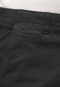 Black denim pants with a smooth texture, featuring a belt looped waistband and a subtle back pocket detail. Plain design, no visible patterns.