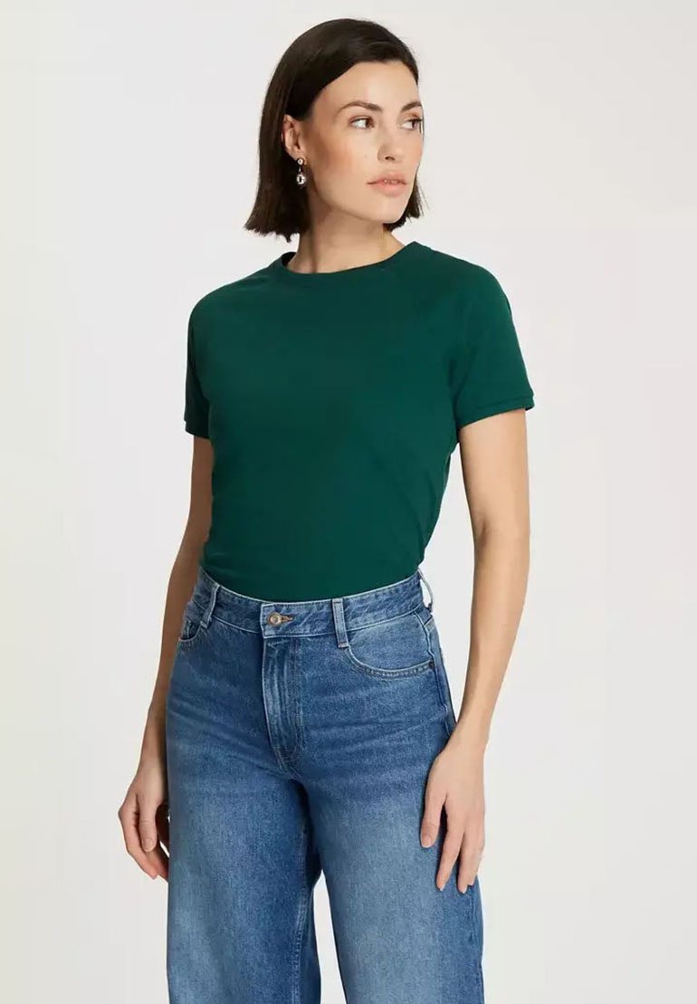 Zielona koszulka z krótkim rękawem o klasycznym okrągłym dekolcie, zestawiona z jeansami w kolorze niebieskim o wysokim stanie. Materiał wydaje się miękki i gładki.