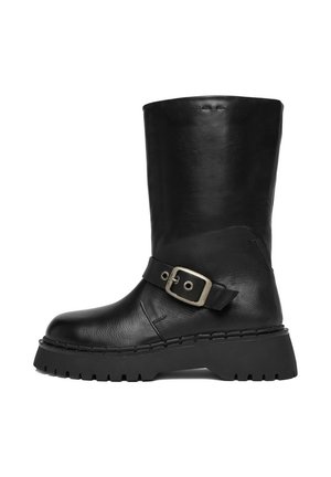 Stivale nero in pelle a metà polpaccio con suola carrarmato e cinturino decorativo con fibbia d'argento intorno alla caviglia.